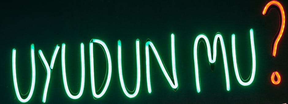 Vibrant neon sign 'Uyudun Mu?' glowing against a black background in Istanbul, Turkey.